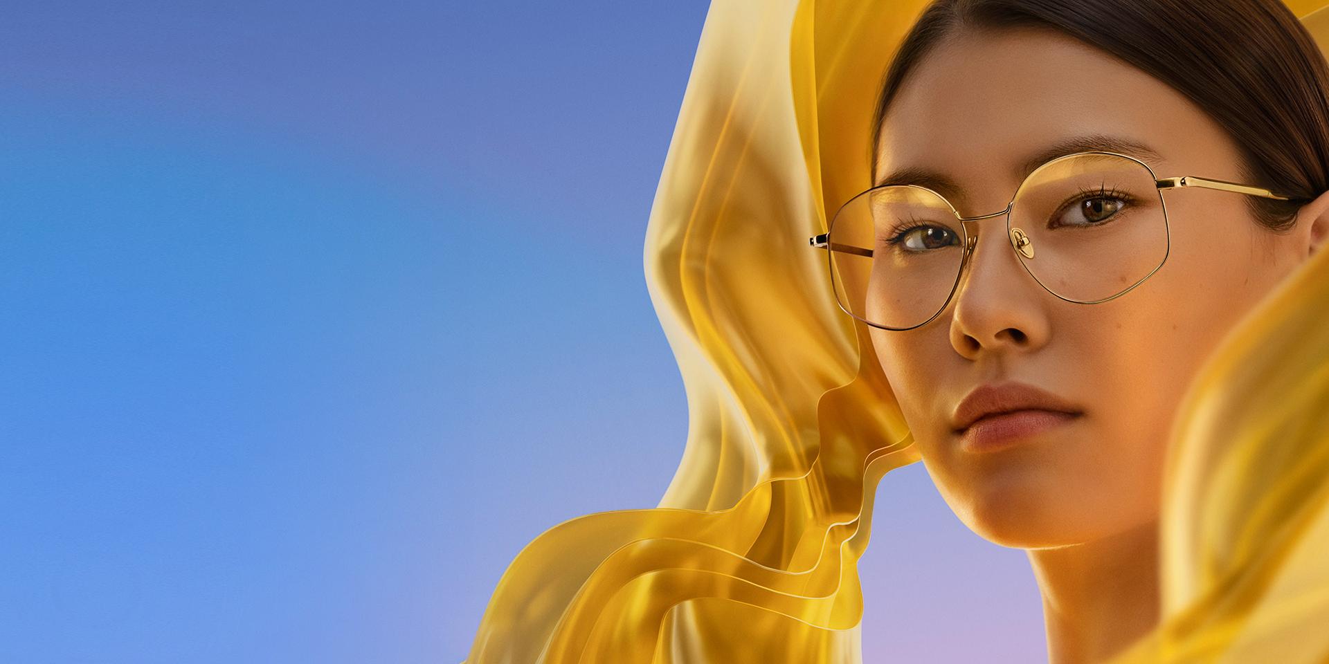 A woman wearing clear eyeglasses with ZEISS DuraVision Gold UV, adding a subtle but distinctive golden reflex to the lenses.