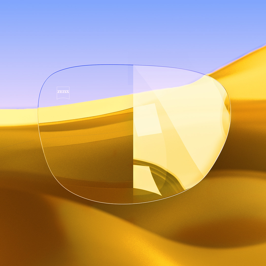 A split lens, one side clear and clean featuring ZEISS DuraVision Gold UV and the other side showing strong light reflections on the lens. 