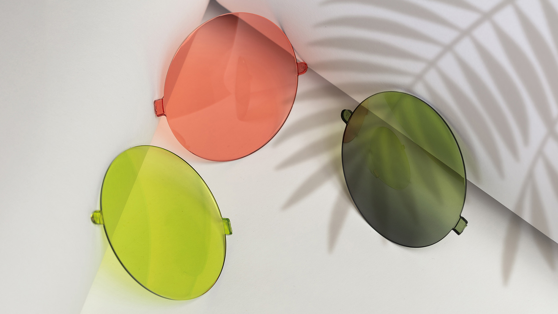 Photo of three sunglasses lenses (yellow, green, pink)