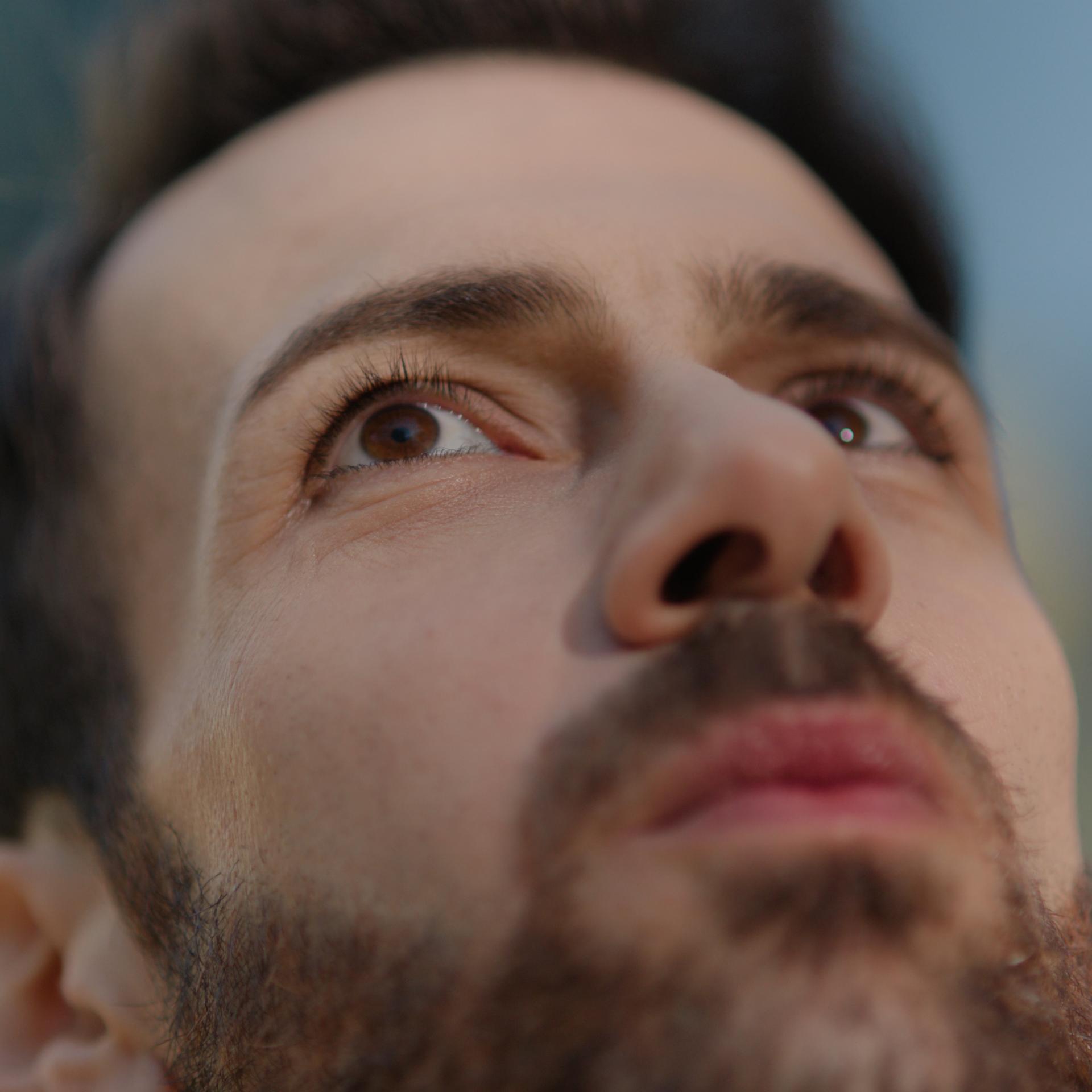 Close-up of a man's face looking upward, emphasizing his eyes and clear vision following LASIK surgery.