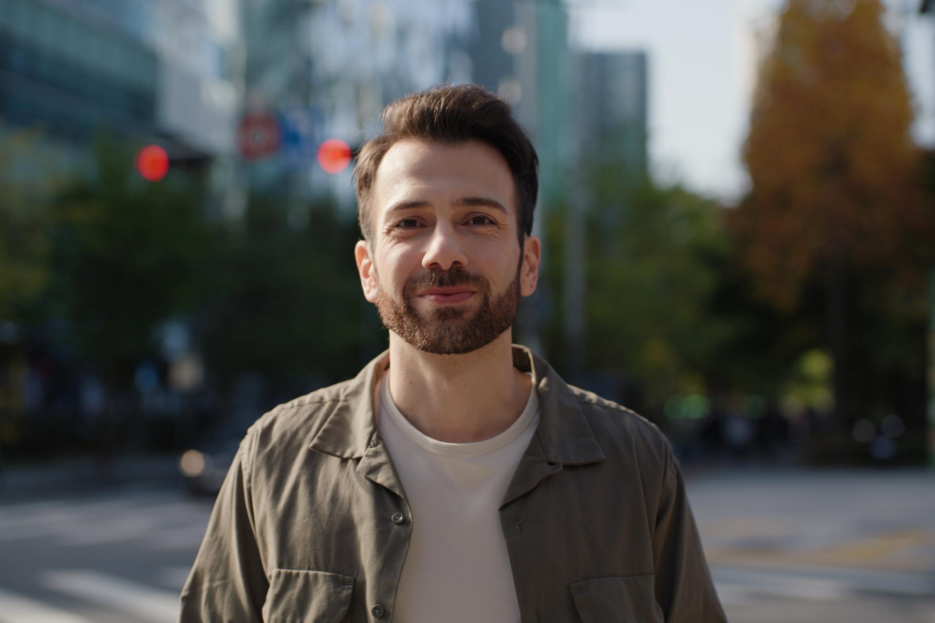 Bearded man smiling outdoors in a city environment, symbolizing confidence and visual freedom after LASIK treatment.