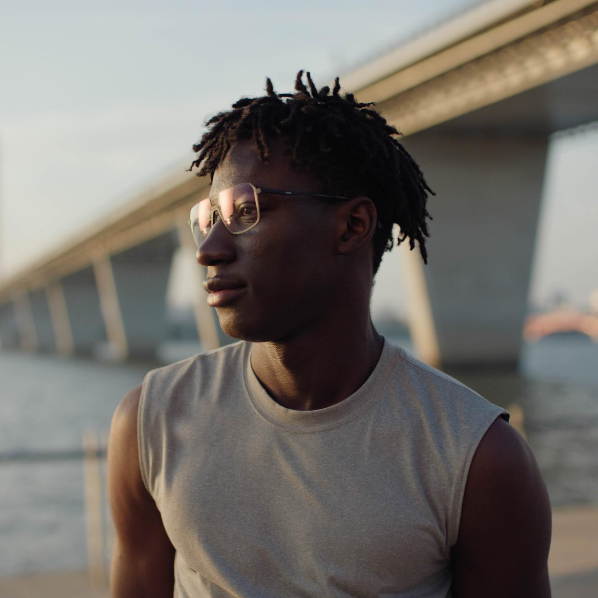 Man wearing glasses by a river during sunset, reflecting potential residual vision problems such as glare, halos, or double vision following LASIK surgery.