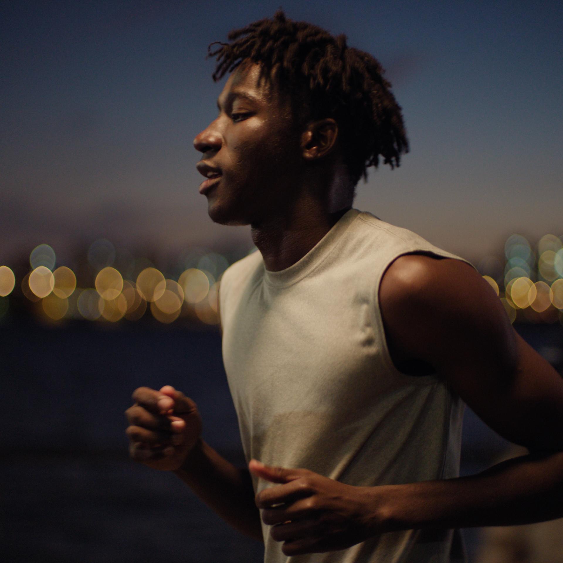 Athletic man running confidently at night with city lights in the background, symbolizing visual freedom after LASIK treatment.