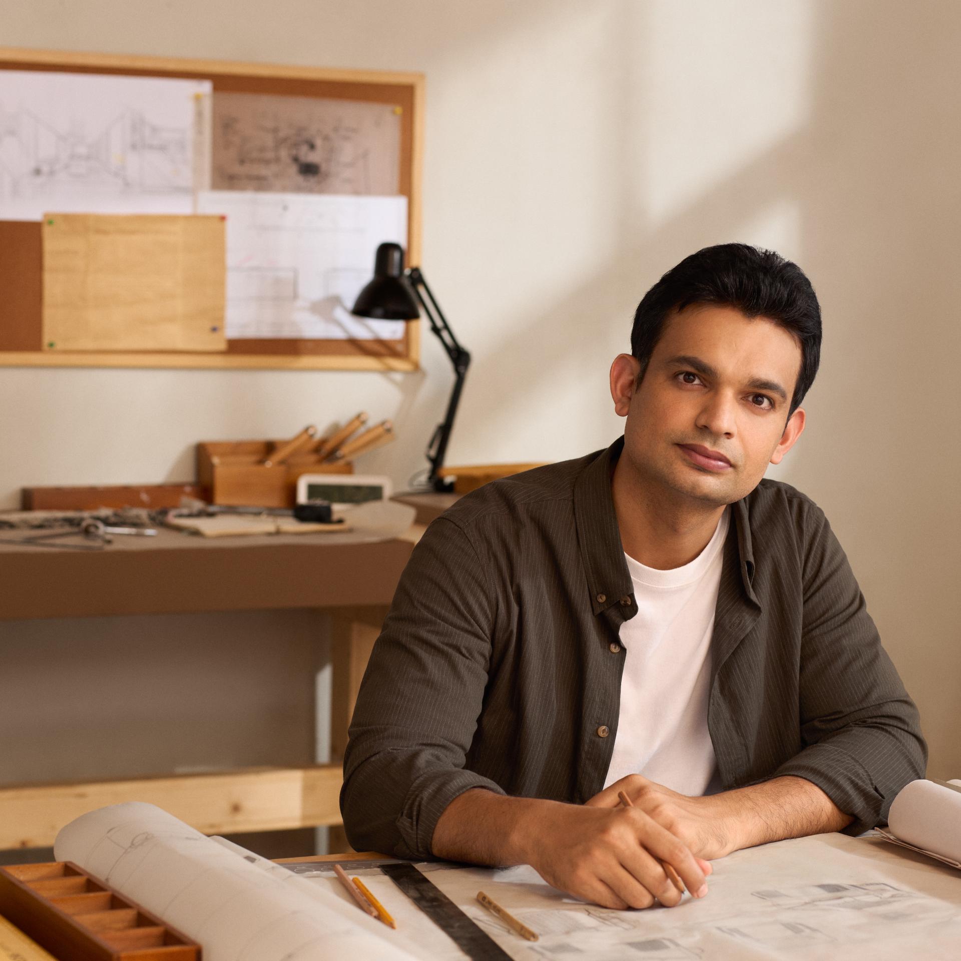 Man sitting at a desk in a creative studio, symbolizing clear vision and concentration following ZEISS SMILE pro eye surgery.