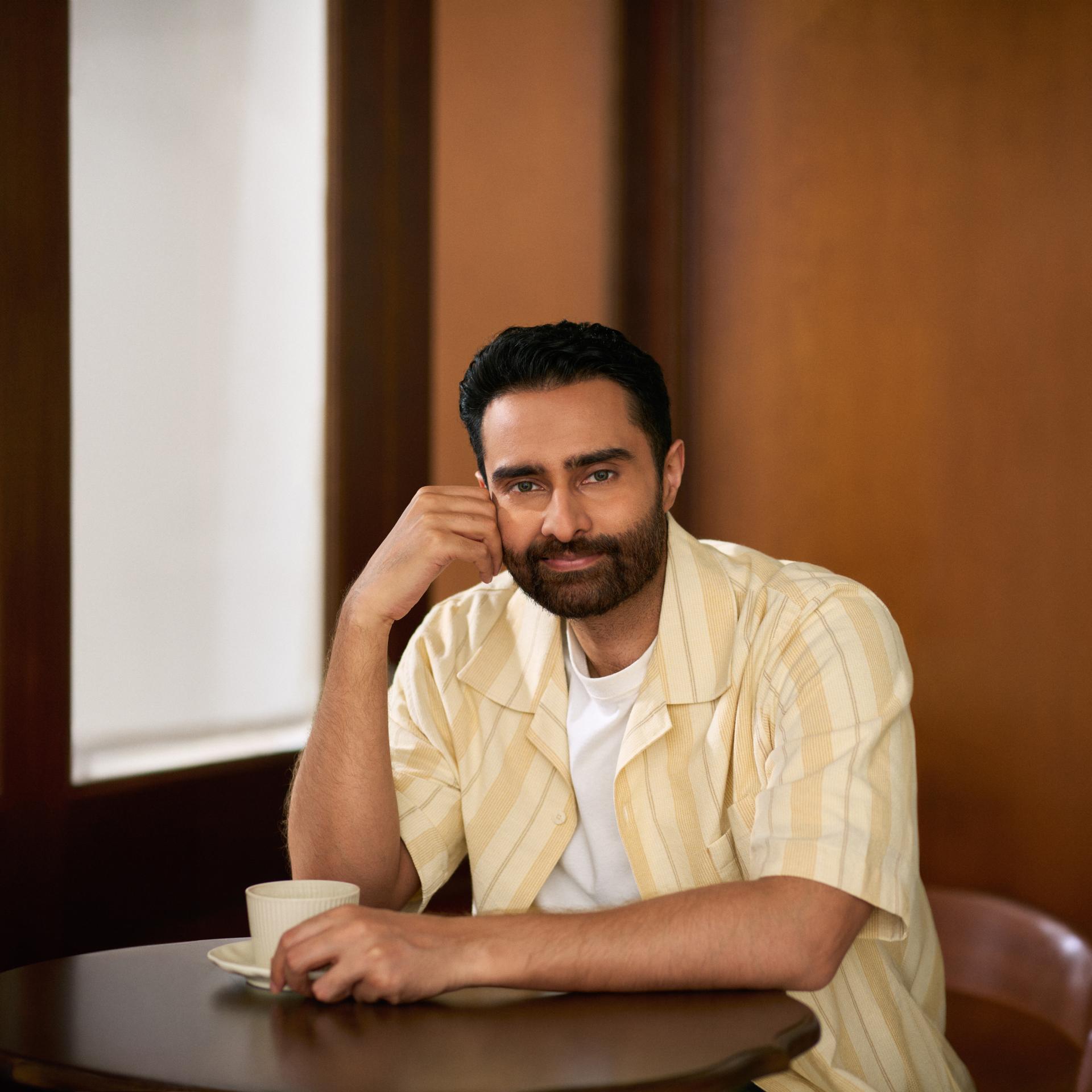 Confident man enjoying coffee at a café table, representing a relaxed lifestyle after laser vision correction with ZEISS SMILE pro. 