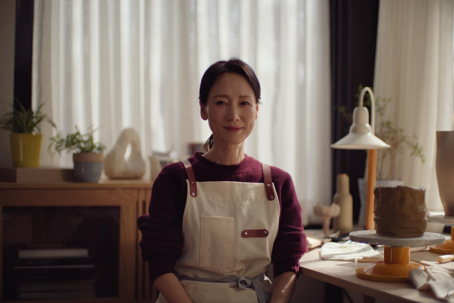 Middle-aged asian woman looking calmly into the camera wearing an apron.