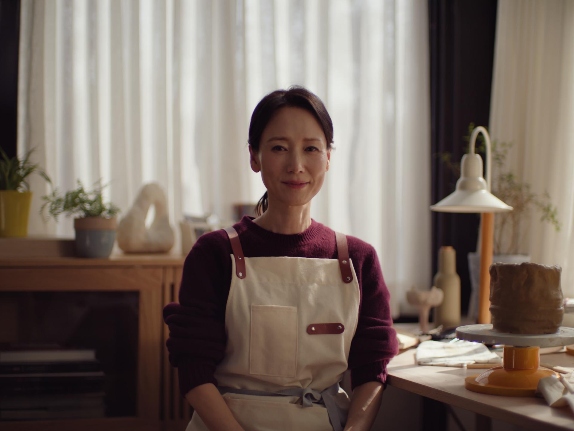 Middle-aged asian woman looking calmly into the camera wearing an apron.