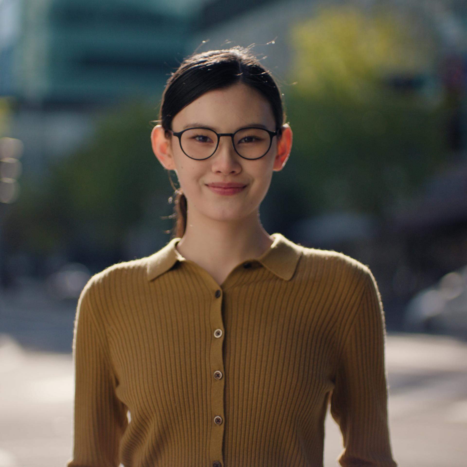 Young woman wearing glasses in bright daylight, suggesting a ZEISS SMILE candidate before undergoing vision correction.