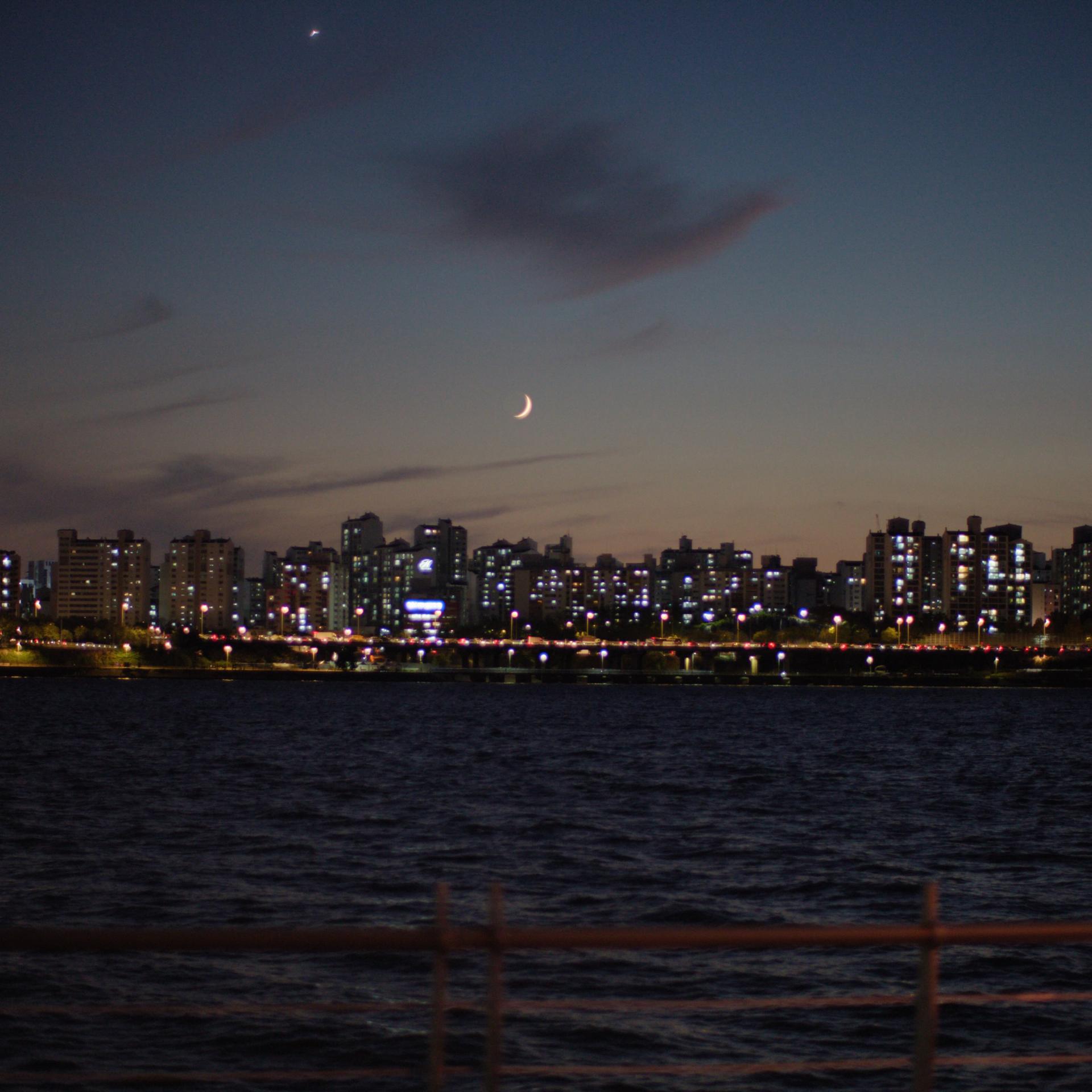 Nighttime city skyline with reflections on water, representing improved night vision after lenticule extraction with ZEISS SMILE pro.