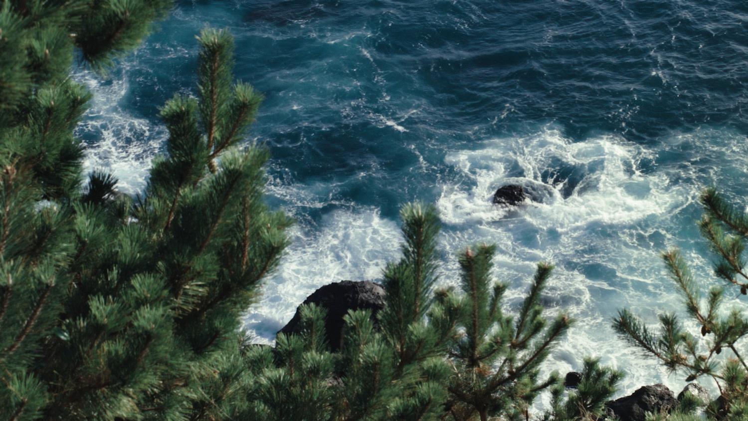 Waves crashing on rocks by the ocean, reminding patients to avoid water in the eyes after vision correction surgery.