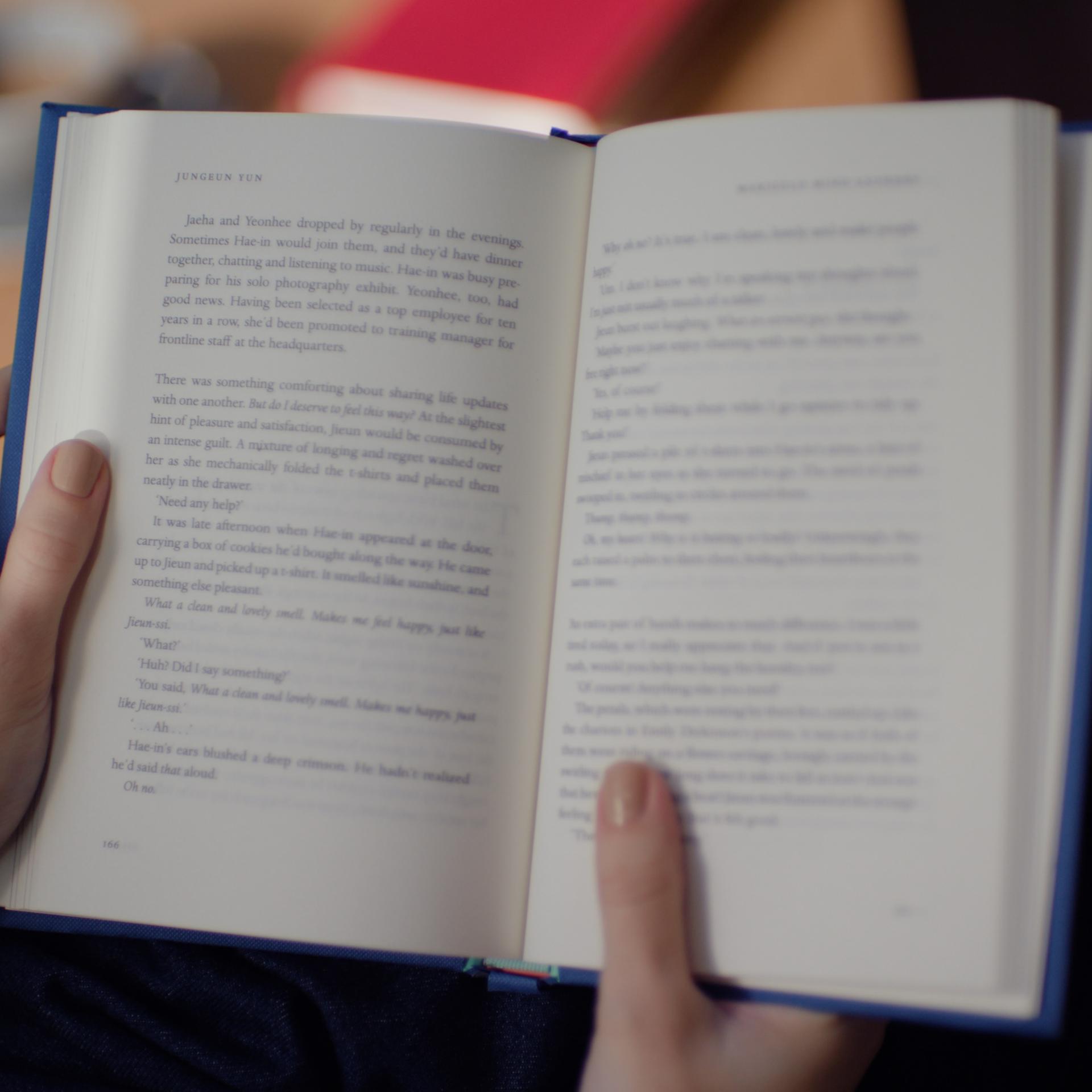 Hands holding a book in clear focus, symbolizing the restored ability to read comfortably after PRK laser eye surgery.