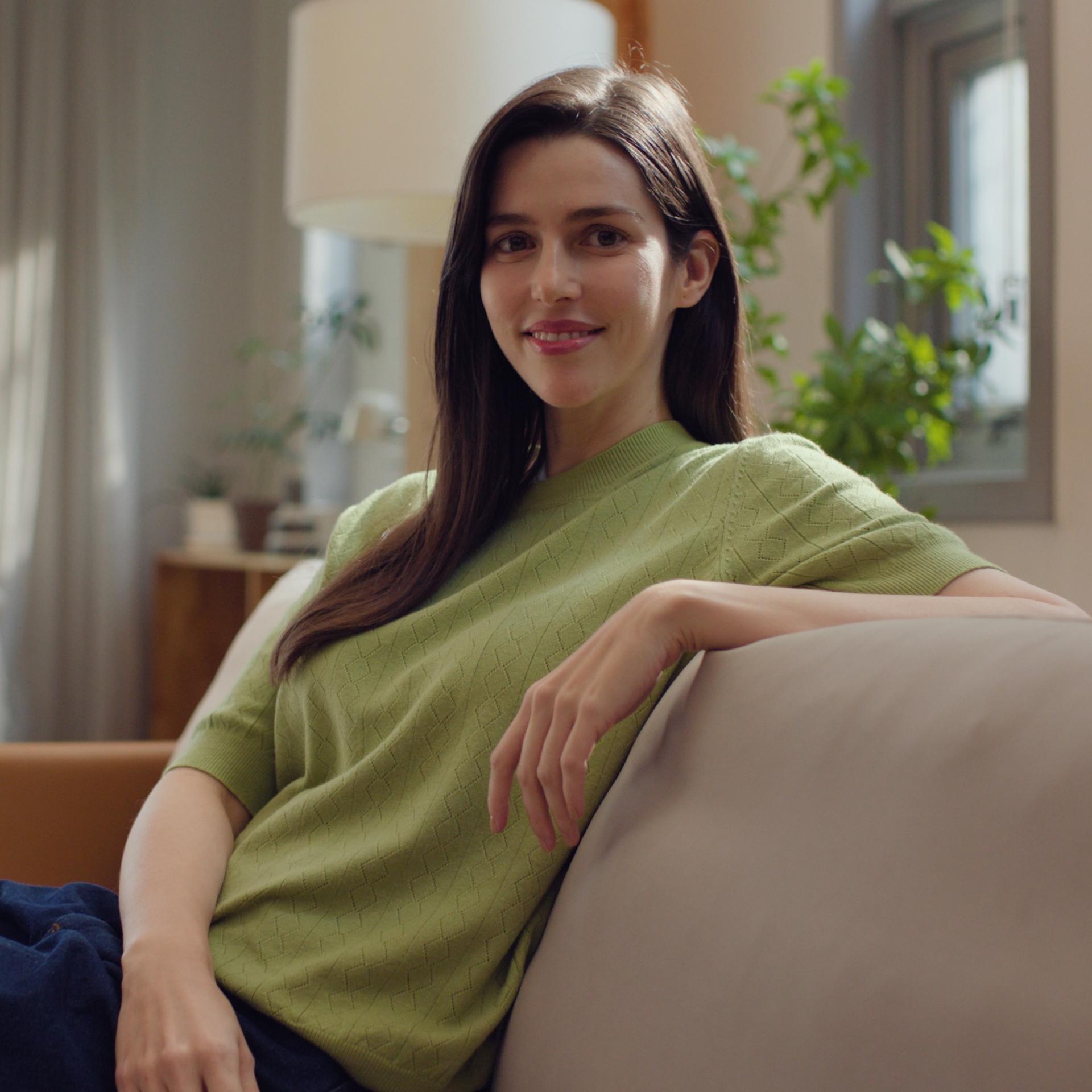 Woman smiling peacefully in a living room setting, reflecting visual independence and comfort post-surgery with ZEISS SMILE.
