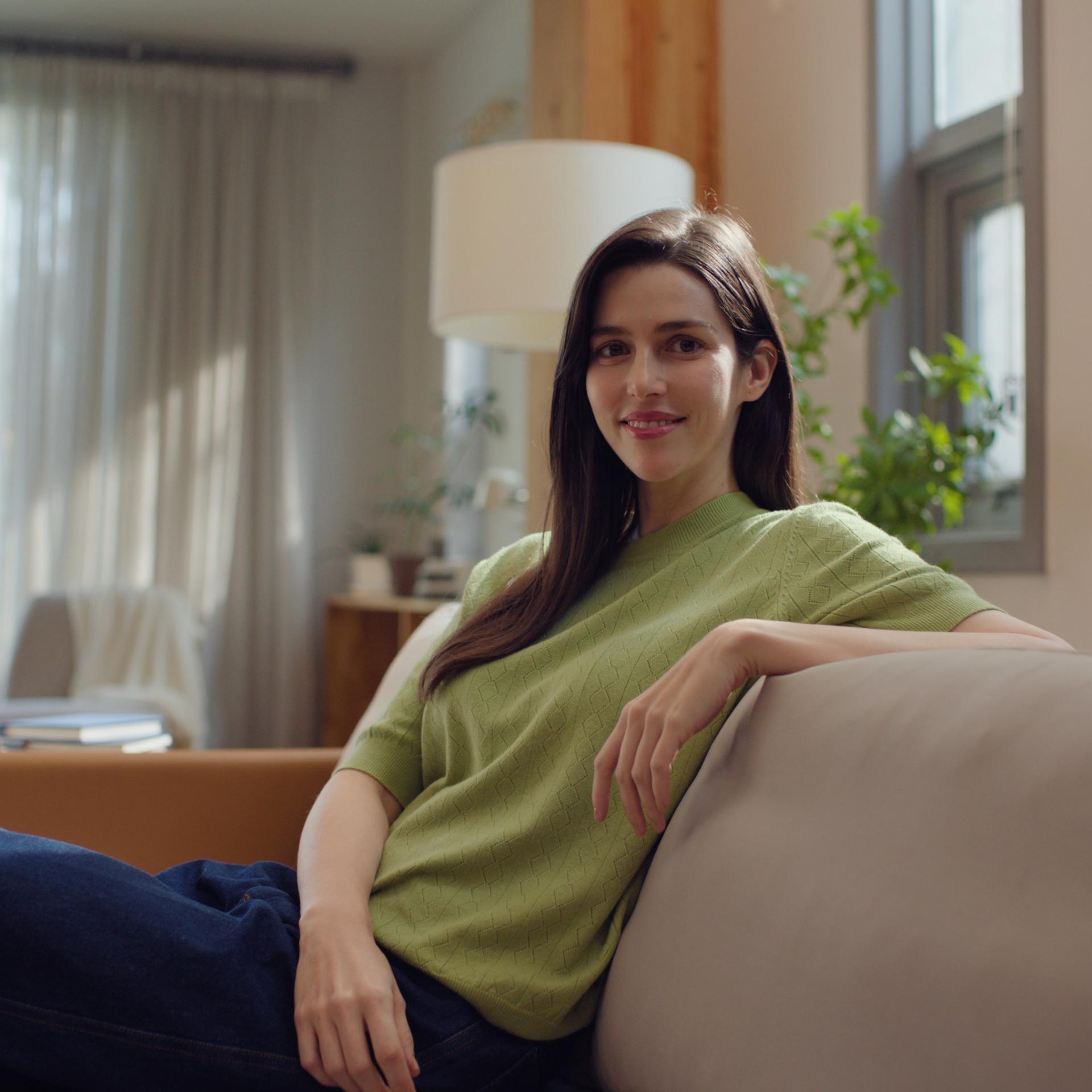 Woman smiling peacefully in a living room setting, reflecting visual independence and comfort post-ZEIS SMILE surgery.