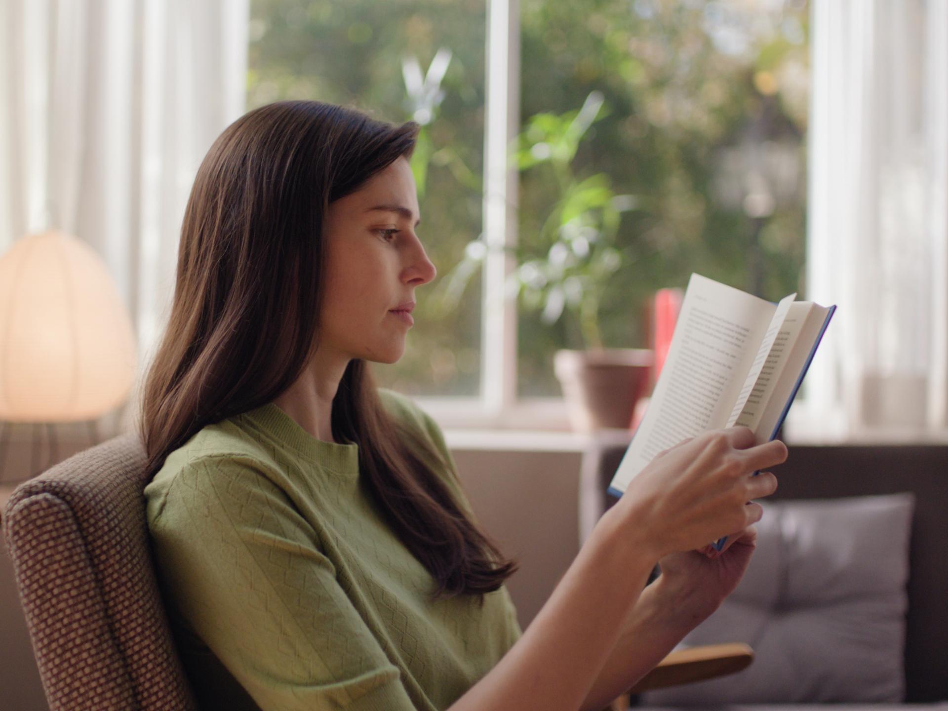 Woman reading comfortably in natural light, representing sharp, unaided vision after ZEISS SMILE pro treatment.