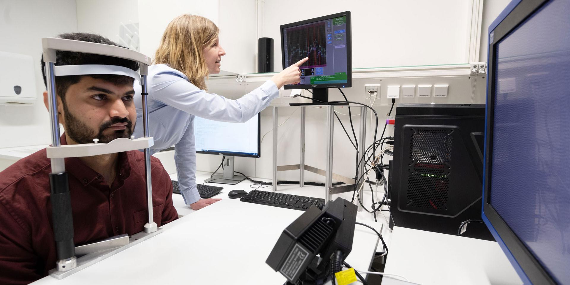 Female scientist shows visual behavior detection of a man's eyes on monitor