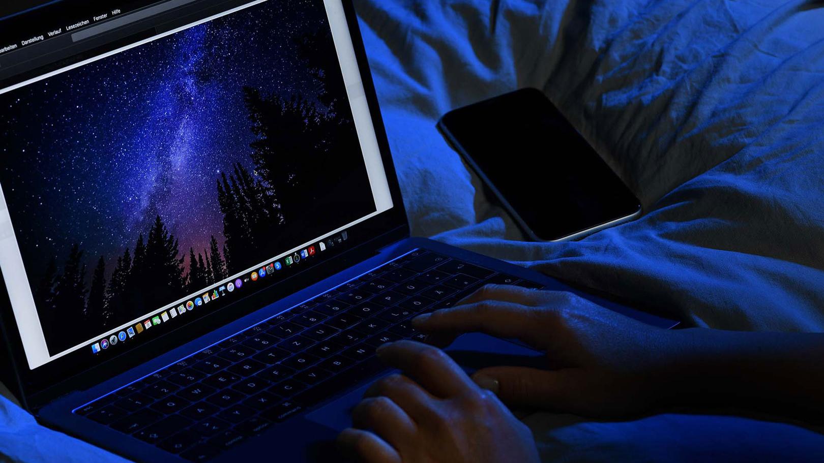 Typing on a notebook in a dark room with blue light all around.