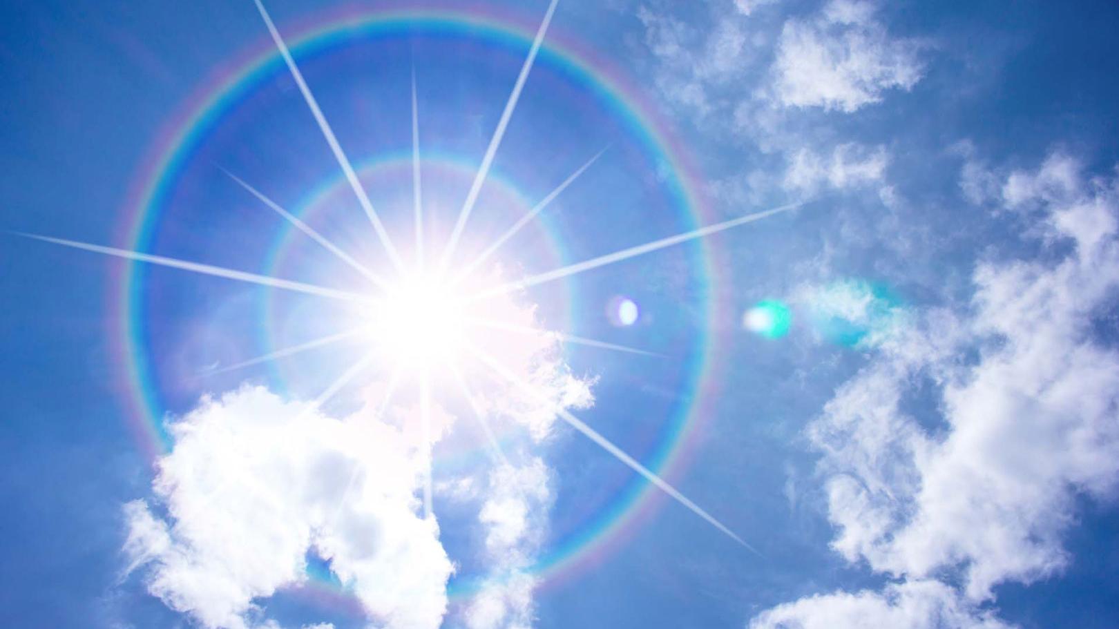 Blue sky with shining sun and a rainbow