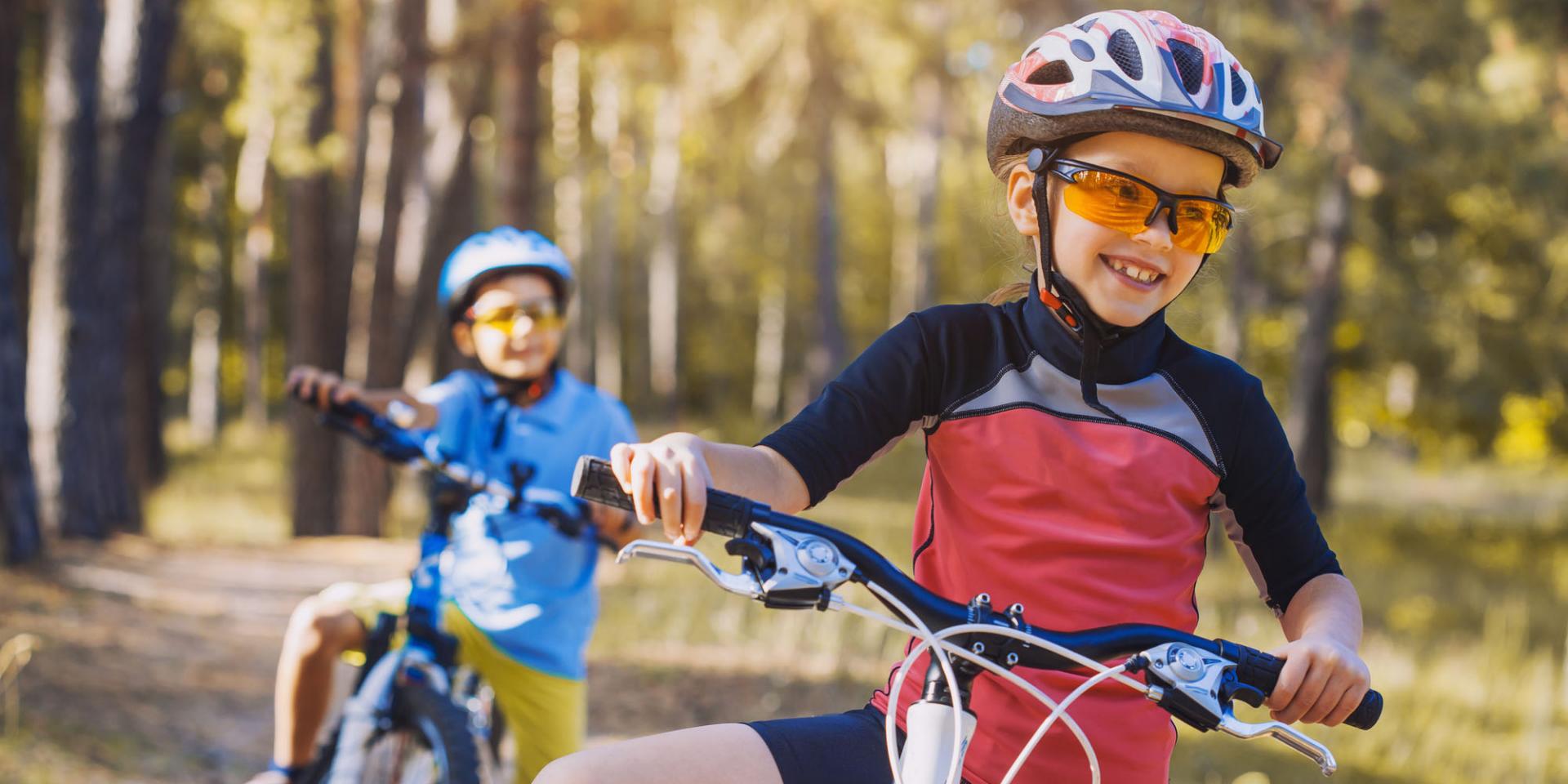 Kids on a bicycles in the sunny forest. children cycling outdoors in helmet