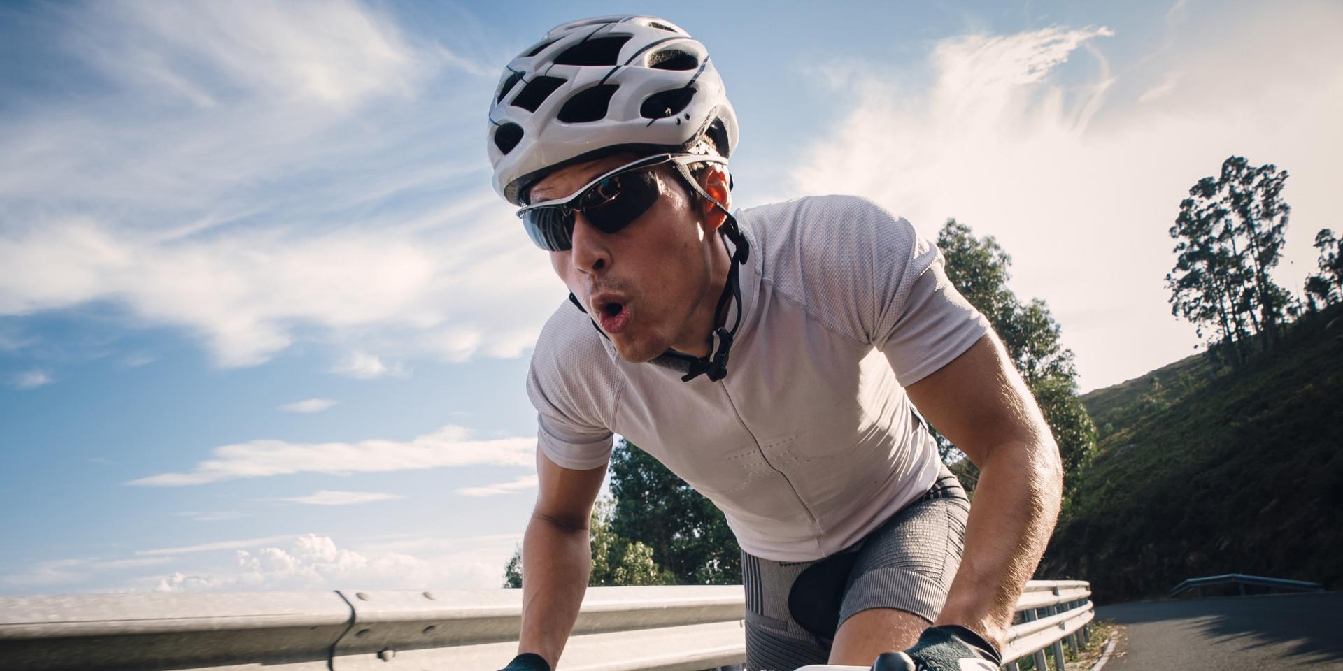 Man cycling in the road with maximum effort.