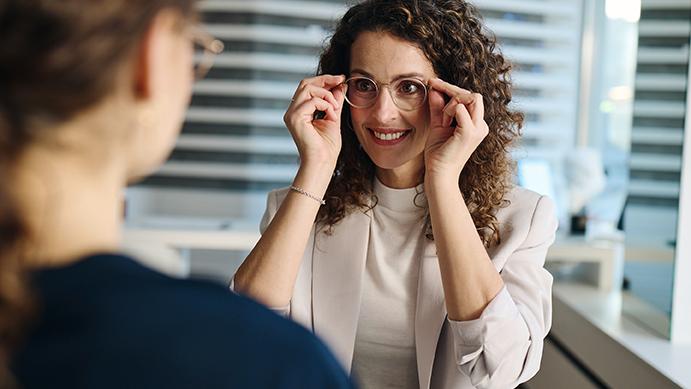 Woman looks enthusiastic as she wears her new ZEISS spectacles for the first time
