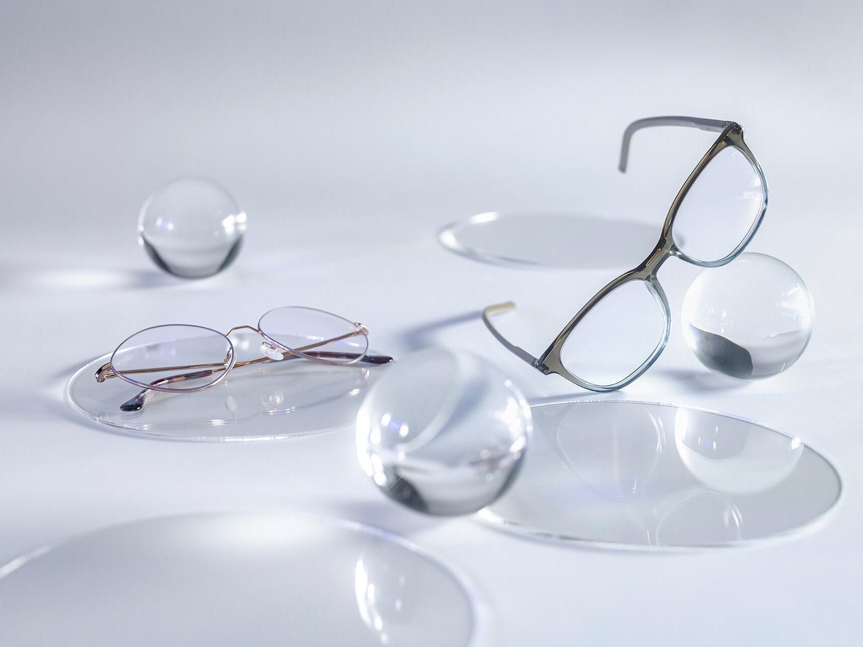 Glasses with ZEISS lenses that have the DuraVision® Silver coating and show no reflections compared to the surrounding glass spheres.
