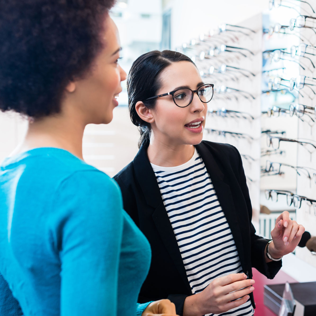 Zwei Frauen schütteln sich in einem Optikergeschäft die Hand.