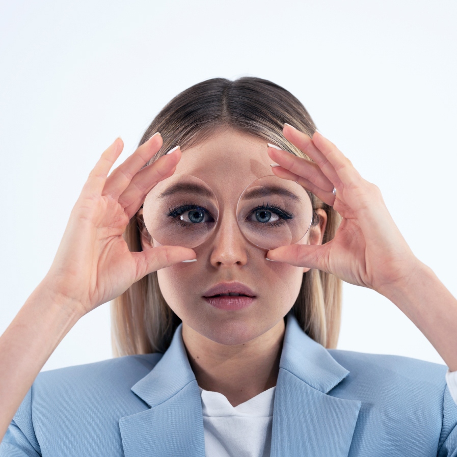 Une jeune femme tient deux verres épais devant ses yeux pour montrer l’effet « fisheye ».