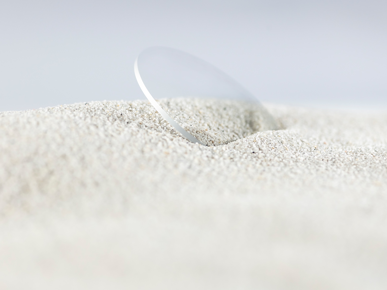 A ZEISS lens with a durable coating is covered in rough sand but still scratch free.