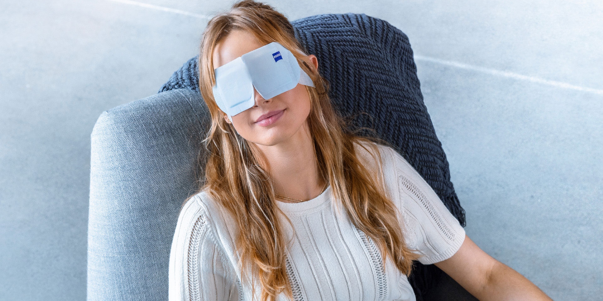 A women wearing ZEISS Warm Eye Mask and relaxing in a chair.