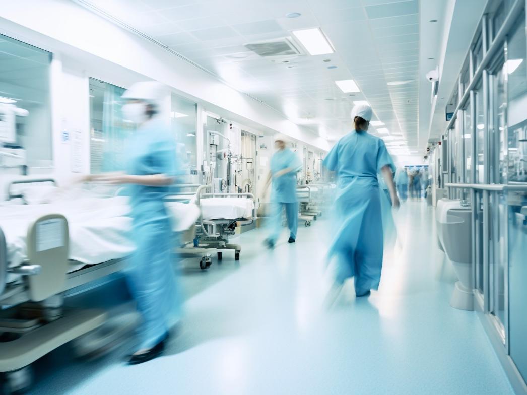 Long exposure blurred motion of medical doctors and nurses in a hospital ward wearing blue aprons, walking down a corridor - Generative AI