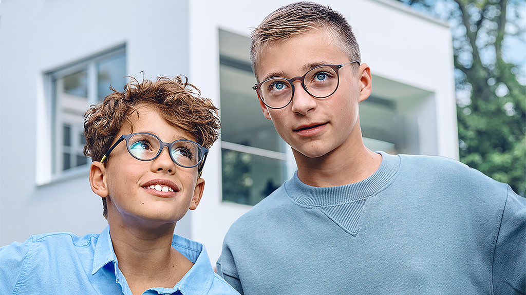Ein kleiner Junge richtet den Blick nach oben, auf einen Teen. Beide Jungen tragen eine ZEISS SmartLife Young Brille mit Einstärkengläsern